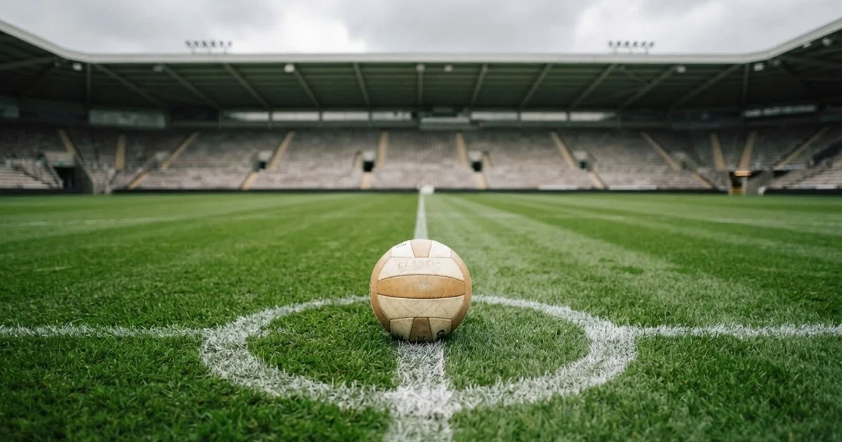 Ein Fussball liegt auf dem Anstosspunkt eines frisch gemähten Rasens, dahinter eine grosse Tribüne unter bewölktem Himmel